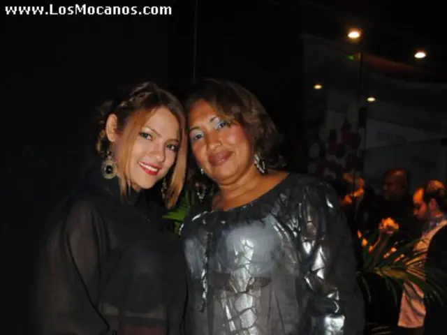 In this image in the front there are women standing and smiling. In the background there are...