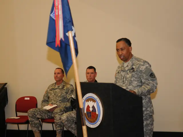 In this image we can see three men. They are wearing army uniform. One man is standing. In front of...